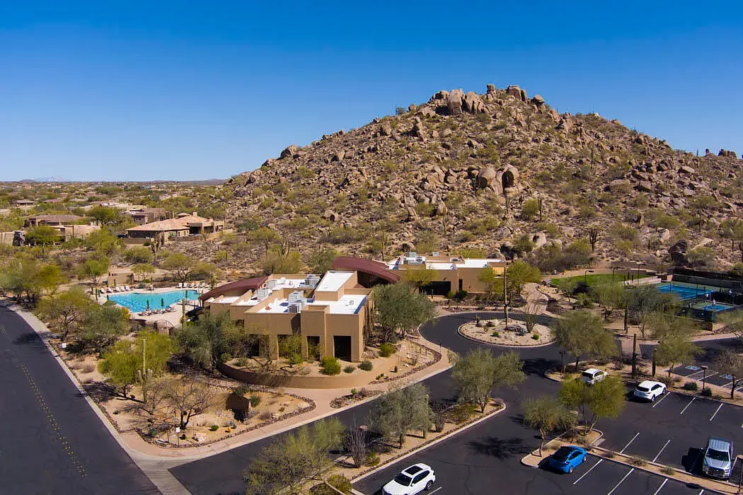 Aerial view of the Winfield community clubhouse and desert landscaping below a rocky boulder-covered mountain